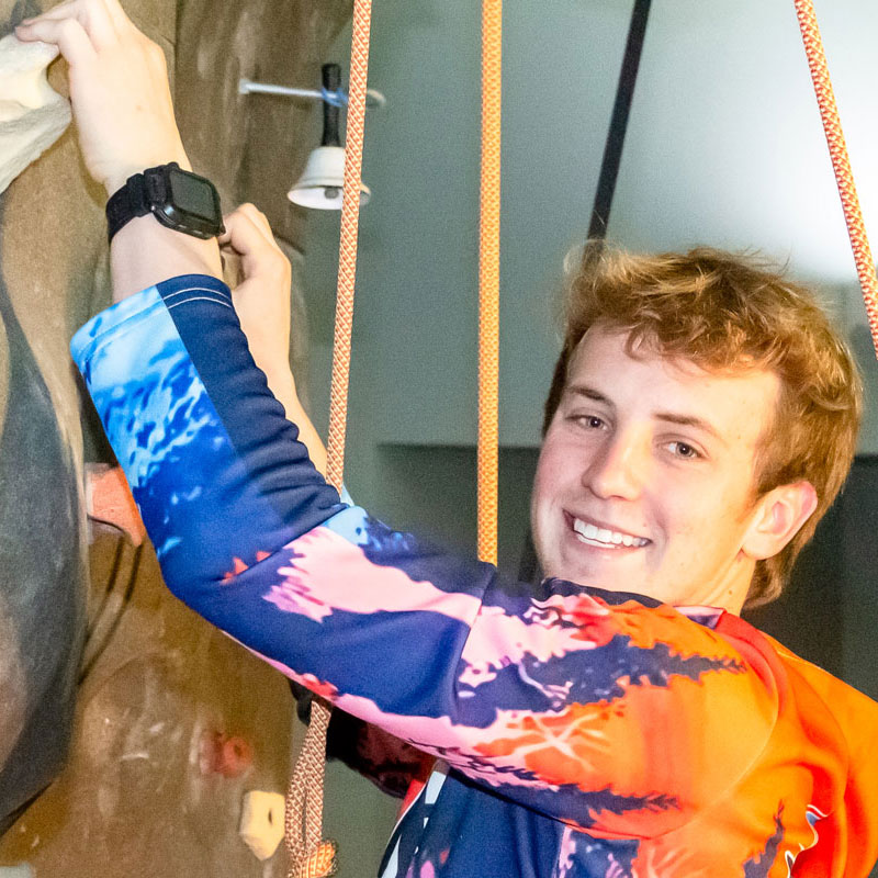 A Young Caucasian Male Smiling While Rock Climbing | Kroc Center Quincy, IL