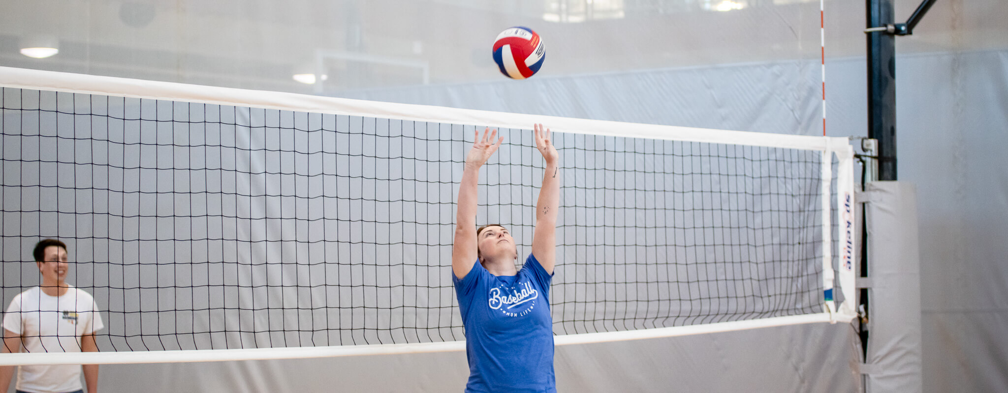 Young women playing volleyball. Setting at the volleyball net.